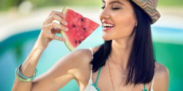 Young woman with summer hat bites juicy watermelon