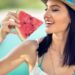 Young woman with summer hat bites juicy watermelon